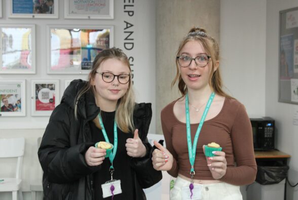 Two happy students holding cup cakes